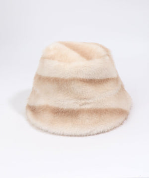 A fuzzy faux fur bucket hat in a soft beige and cream color-blocked pattern, photographed on a seamless white background.