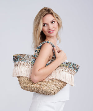 Straw beach basket bag in natural with sequin detailing and fringed accents, zip closure, interior pockets, lightweight spacious design for beach and summer travel use.