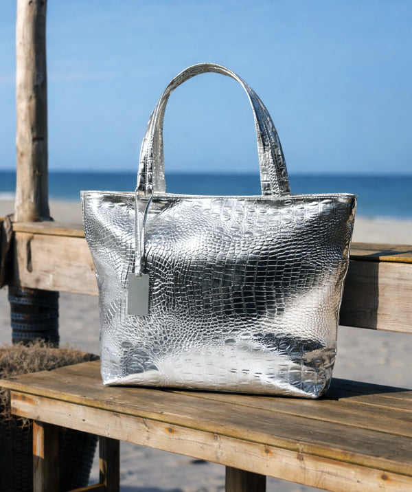 Metallic faux leather tote bag in gold with top handles, zip closure, interior pockets, spacious structured design for travel, beach and summer use.