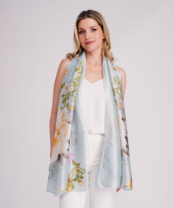 Blue oblong scarf featuring a vibrant abstract floral print in rich blue tones for an elegant statement finish. Crafted from soft, lightweight silk-feel fabric with polished edging for a refined look. Sized 85 x 180 cm for versatile styling as a scarf, wrap, or shawl.