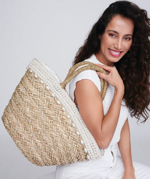 Straw beach basket in natural with pearl and bead embellishment, zip closure, twin top handles, interior pocket, lined spacious design for summer and travel use.