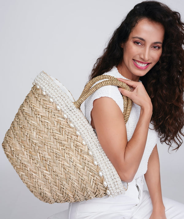 Straw beach basket in natural with pearl and bead embellishment, zip closure, twin top handles, interior pocket, lined spacious design for summer and travel use.