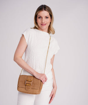 Straw crossbody bag in natural tones with snap closure, detachable chain strap, interior pocket, compact lightweight design for travel, city and everyday use.